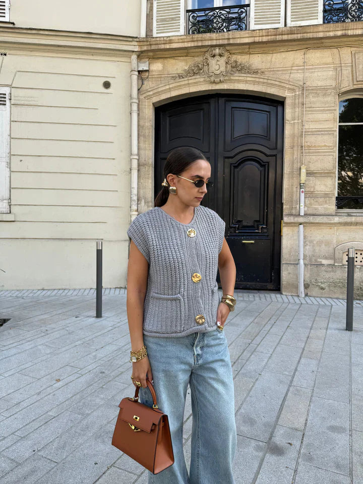 Frau in grauer Strickweste und blauer Jeans, trägt braune Handtasche. Modetrend, Streetstyle, lässiger Look, urbane Mode, Damenbekleidung.