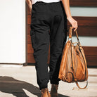 Damen-Cargohose in Schwarz, kombiniert mit brauner Lederhandtasche. Modetrend, lässiger Stil, ideal für Freizeit und Streetwear.