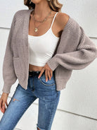 Damenmode: Beige Strickjacke über weißem Top, kombiniert mit zerrissenen Jeans. Trendige Herbstmode, lässiger Look, stilvolle Outfits.