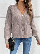 Damen-Strickjacke in Beige mit V-Ausschnitt und Knopfleiste, kombiniert mit blauer Jeans und schwarzer Handtasche. Modetrend Herbst 2023.