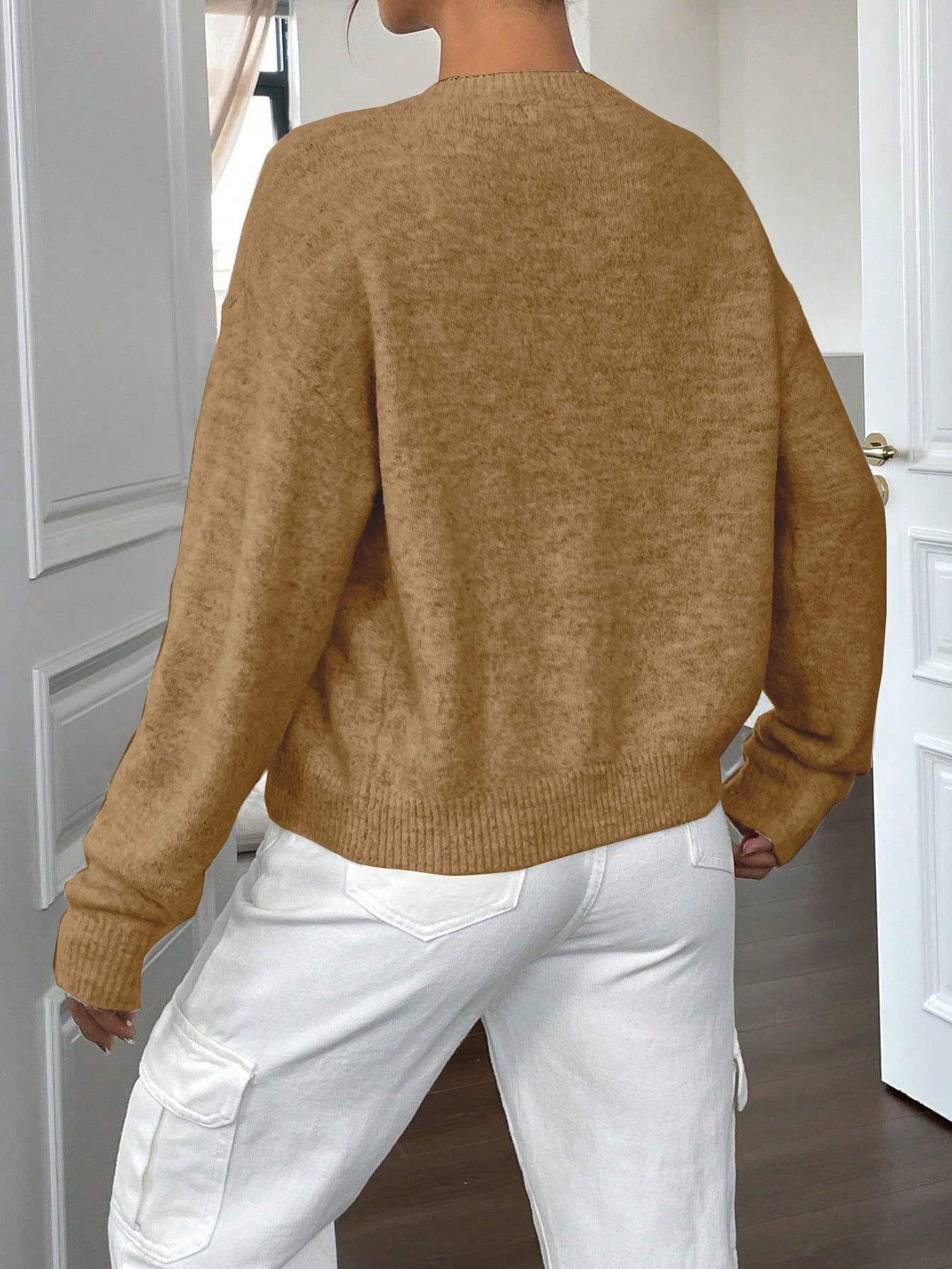 Damenpullover in Kamelbraun, weiches Strickmaterial, kombiniert mit weißen Cargohosen. Modischer Herbstlook, ideal für kühle Tage.