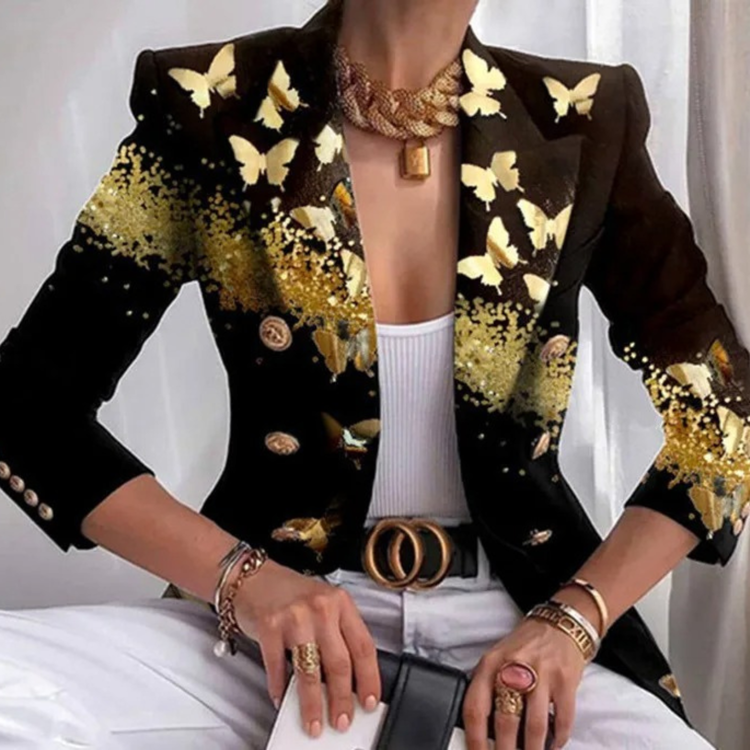 Eleganter schwarzer Blazer mit goldenen Schmetterlings- und Glitzerdetails, ideal für modische Anlässe. Perfekt kombiniert mit weißem Top und Hose.