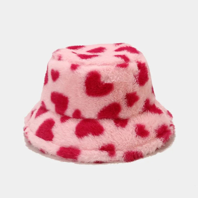 Rosa Plüsch-Bucket-Hat mit roten Herzmustern, ideal für Wintermode. Flauschiger Damenhut, warm und stilvoll für Outdoor-Aktivitäten.