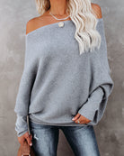 Grauer Oversize-Pullover für Damen, lässig und schulterfrei, kombiniert mit Jeans. Perfekt für Herbstmode und gemütliche Outfits.