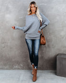 Graues Oversize-Pullover-Outfit mit blauer Jeans und braunen Stiefeletten. Perfekt für lässige Herbstmode. Trendige Damenbekleidung.