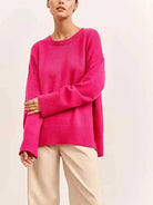 Damenpullover in leuchtendem Pink, oversized Schnitt, kombiniert mit beigen Hosen. Modetrend, Herbstmode, gemütlicher Strickpullover.