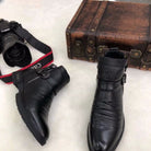 Schwarze Lederstiefel mit Schnallen, neben einer Vintage-Ledertasche und einer Canon-Kamera. Stilvoll, modisch, hochwertiges Schuhwerk.