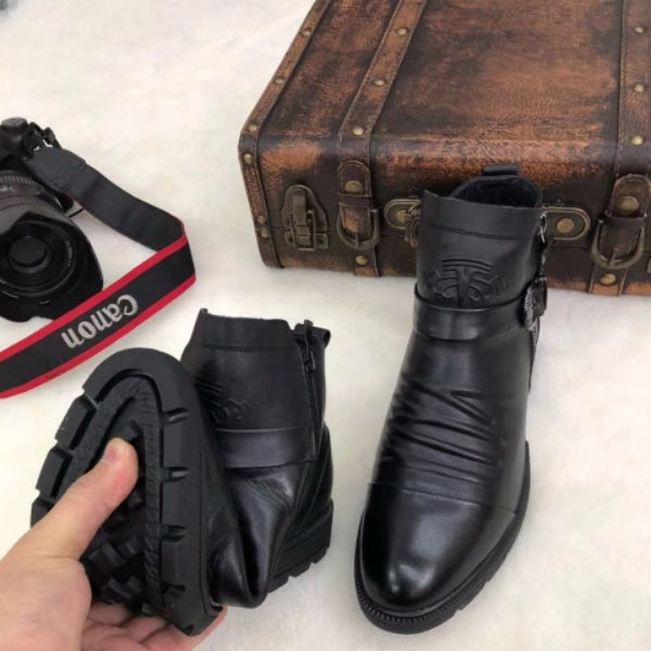 Schwarze Lederstiefel mit robustem Profil, neben einer Vintage-Ledertasche und einer Canon-Kamera. Perfekt für stilvolle Outdoor-Abenteuer.