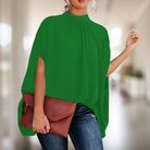 Elegante grüne Bluse mit Stehkragen, kombiniert mit brauner Lederhandtasche und Jeans. Perfekt für stilvolle, moderne Damenmode.