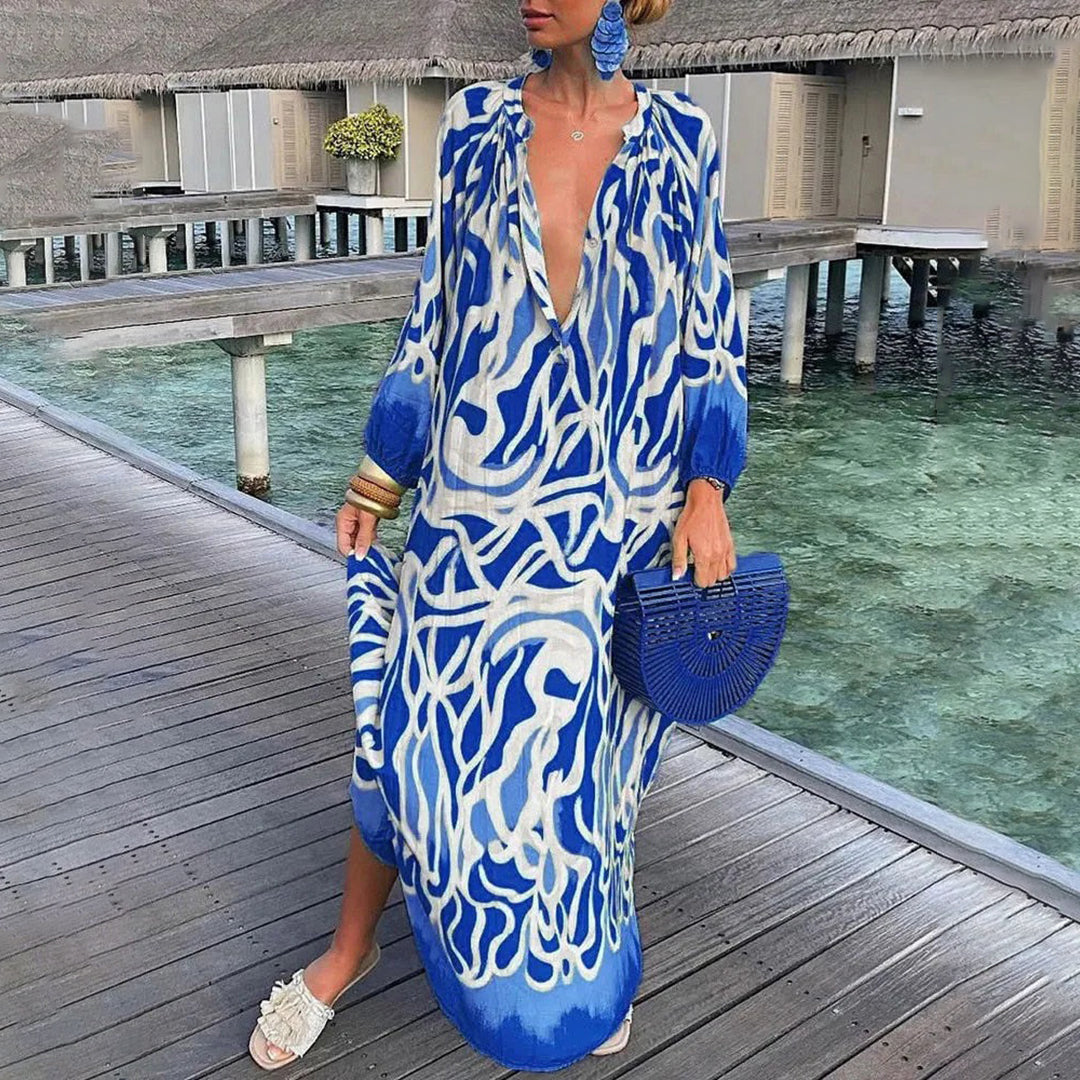 Frau in blau-weißem Kaftan mit tiefem Ausschnitt, hält eine blaue Clutch. Sommermode, Strandkleidung, elegantes Design, tropische Kulisse.