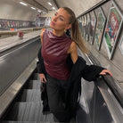 Frau in eleganter, ärmelloser Lederbluse auf Rolltreppe in U-Bahn-Station. Mode, urbane Eleganz, stilvolle Kleidung, modernes Outfit.