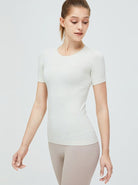 Damen-Sportshirt in Weiß, kurzärmelig, atmungsaktiv, ideal für Fitness und Yoga. Hochwertige Materialien, figurbetontes Design.