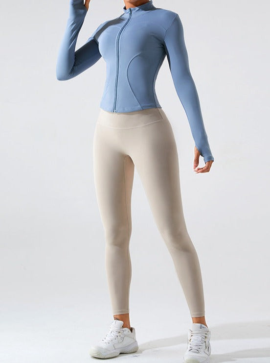 Damen-Sportoutfit: Hellblaues, langärmeliges Oberteil mit Reißverschluss und beige Leggings. Ideal für Fitness, Yoga und Freizeit.