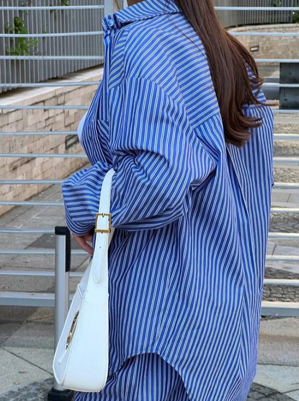 Frau in blau-weiß gestreiftem Hemd mit weißer Handtasche. Modetrend, lässiger Stil, Streetwear, Damenmode, gestreiftes Hemd, Accessoires.