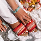 Rote Sandalen mit bunten Verzierungen, ideal für Sommermode. Perfekt kombiniert mit weißem Kleid und Blumenaccessoires. Trendige Damenmode.