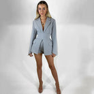 Eleganter grauer Blazer-Overall für Damen, ideal für Business- und Abendanlässe. Modischer Einteiler mit tiefem Ausschnitt und langen Ärmeln.