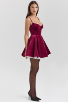 Elegantes rotes Samtkleid mit Spaghettiträgern und ausgestelltem Rock, ideal für festliche Anlässe. Perfekt kombiniert mit schwarzen Strumpfhosen.