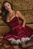 Elegantes rotes Samtkleid mit Spaghettiträgern und Tüllsaum, ideal für festliche Anlässe. Perfekt für stilvolle Abendmode und Partys.